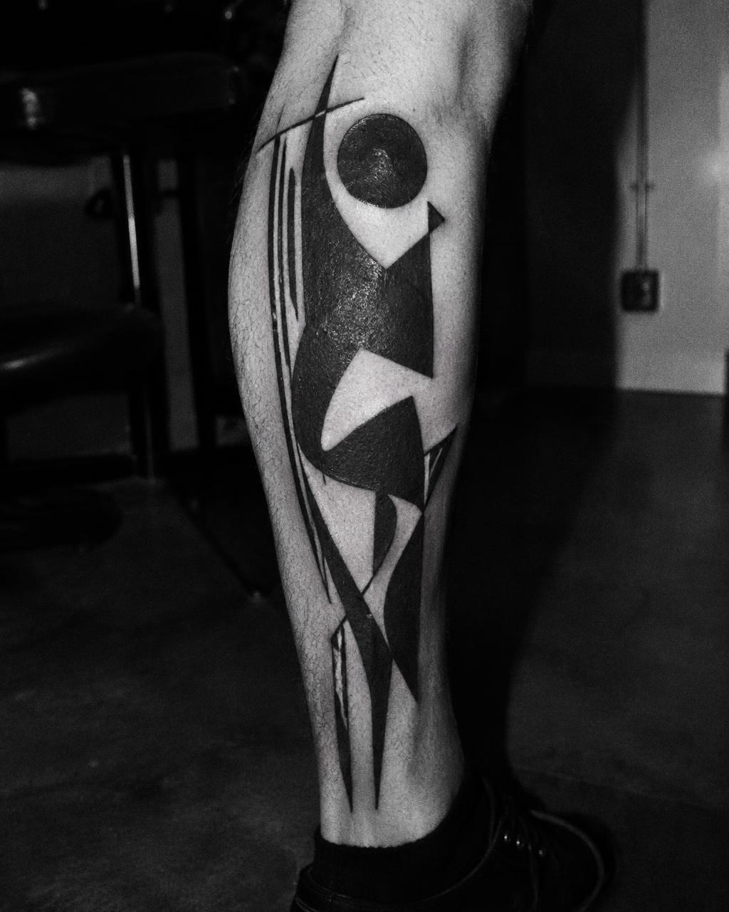 Bold geometric blackwork tattoo on a calf