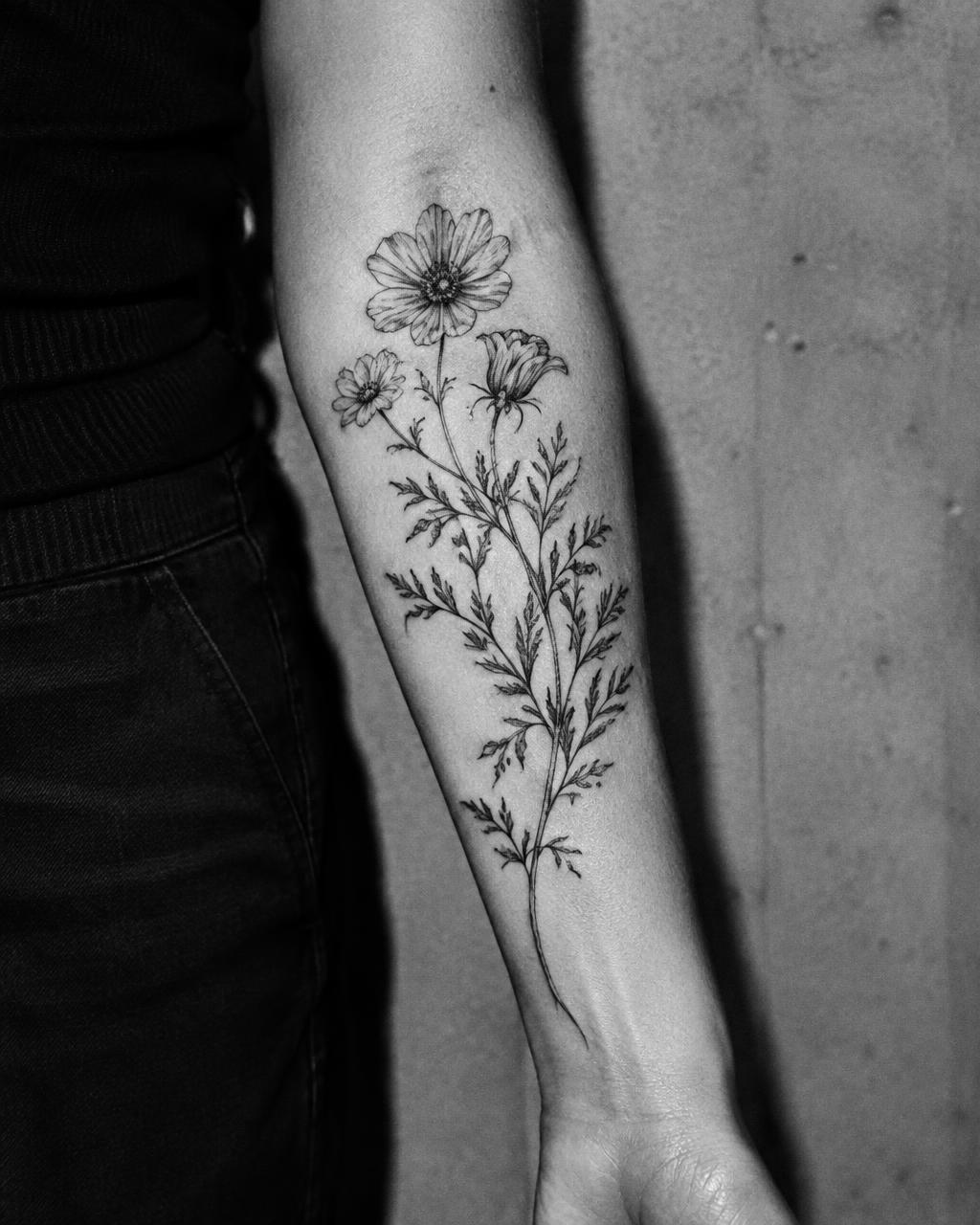 Fine-line botanical flower tattoo on a forearm